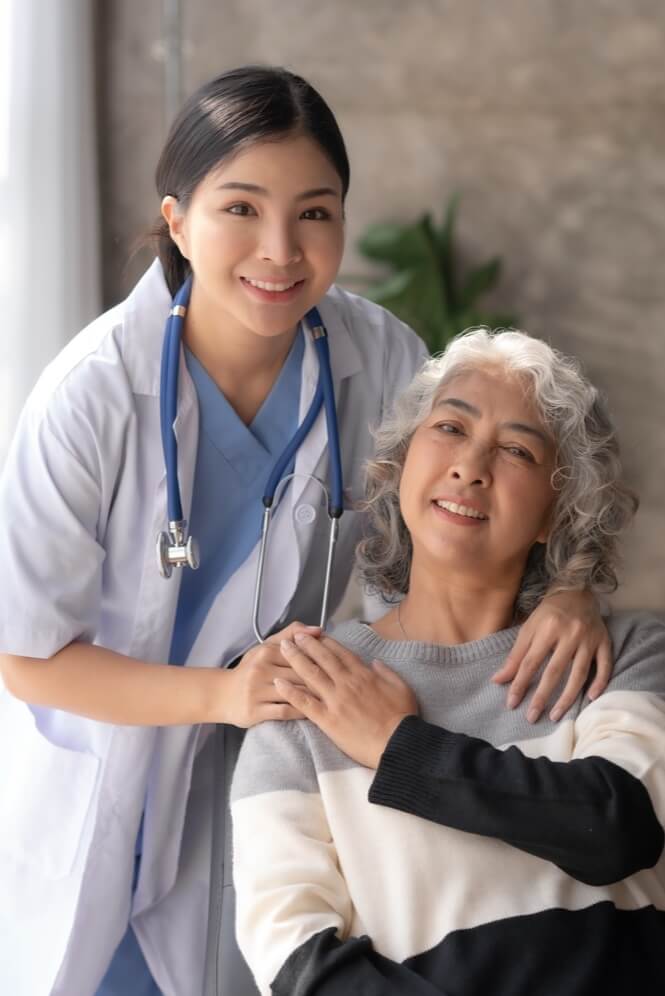 Asian Female Doctor Hugging Elderly Woman in Memory Care Facility Asian Female Doctor Hugging Elderly Woman in Memory Care Facility